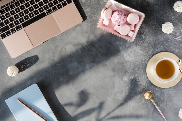 Mesa de escritorio de oficina gris moderna con computadora portátil y otros suministros con taza de té