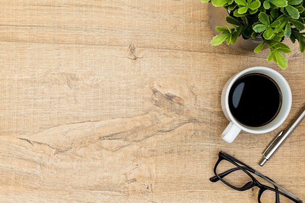 Mesa de escritorio de oficina de madera con café, pluma y gafas.