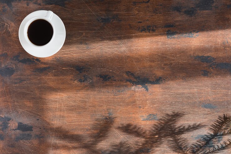 Foto mesa de escritorio de oficina de madera oscura con ordenador portátil y taza de café.
