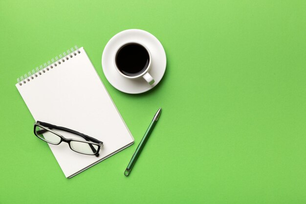 Mesa de escritorio de oficina moderna con cuaderno y otros suministros con taza de café Página de cuaderno en blanco para su diseño Vista superior plana