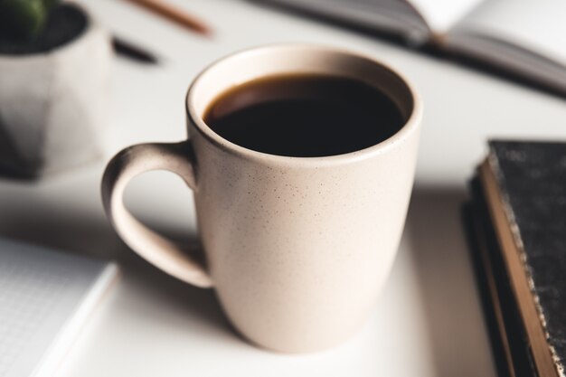 Mesa de escritorio de oficina con suministros, taza de café y flor. Vista superior con espacio de copia