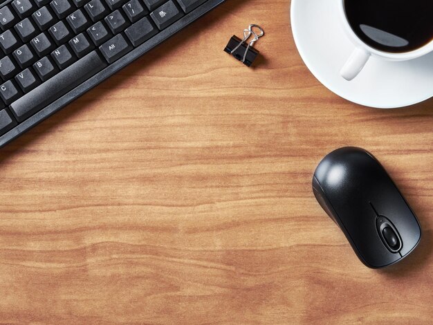 Mesa de escritorio de oficina con teclado y taza de café.