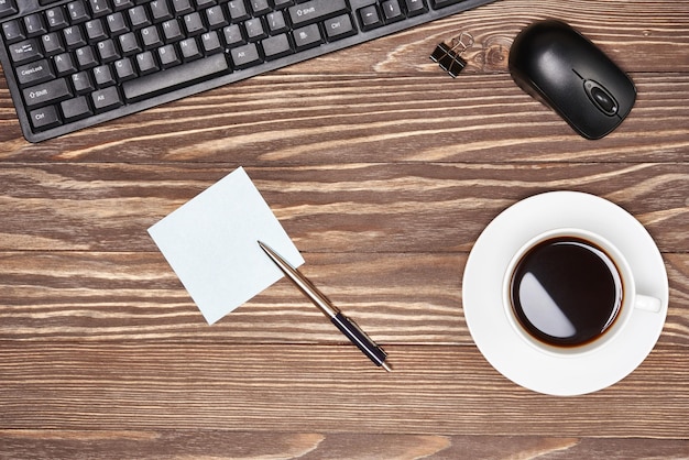 Mesa de escritorio de oficina con teclado y taza de café.