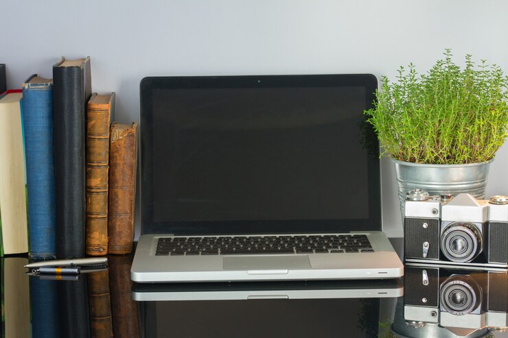 Foto mesa de escritorio de vidrio de oficina con computadora, flores y suministros