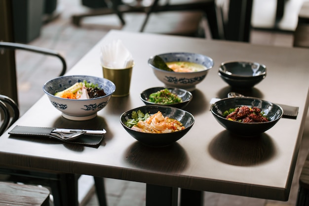 Mesa escura servida com pratos japoneses estilo asiático