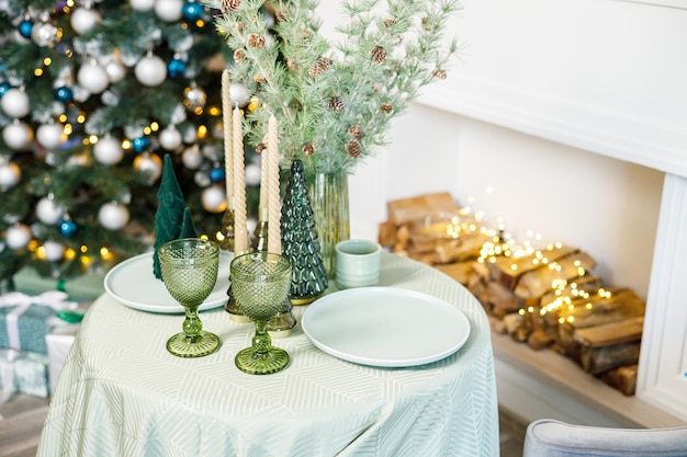 La mesa está puesta cerca del árbol de Navidad para una cena romántica de Año Nuevo Cena festiva de Año Nuevo