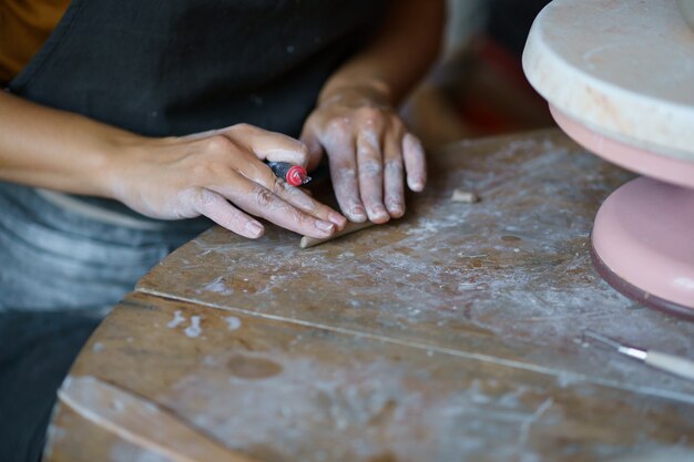 Mesa en el estudio de alfarería con la mano del trabajo maestro en detalles hechos a mano para la decoración de utensilios de cocina de alfarero