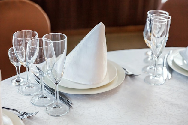 Mesa extravagante posta para jantar com óculos de guardanapo em restaurante de luxo fundo interior perna de casamento