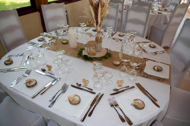 Mesa festiva de casamento branca natural decorada com pratos e copos e buquê de flores no restaurante de casamento