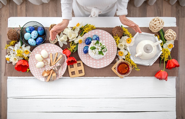 Mesa festiva de Páscoa com bolo caseiro de Páscoa, chá, flores e detalhes de decoração copiam espaço. Conceito de celebração familiar.