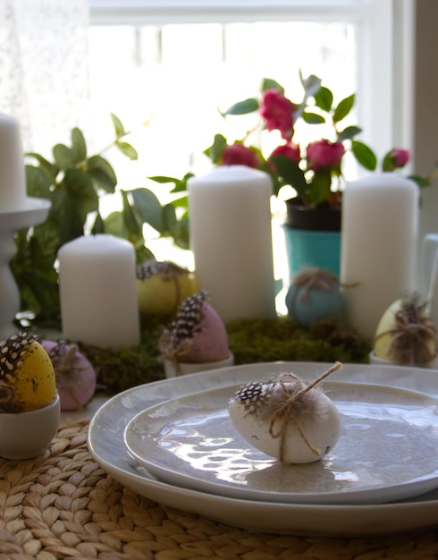 Mesa festiva y decoración primaveral con velas, huevos de Pascua y flores.