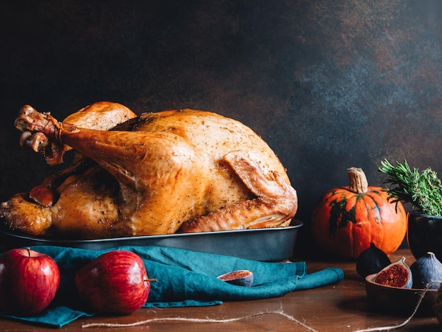 Mesa festiva para el Día de Acción de Gracias con pavo asado entero con higos de calabaza de manzana y hierbas en un mortero