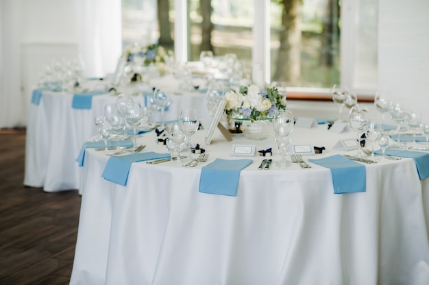 La mesa festiva está decorada en colores claros con servilletas azules y flores sin comida.