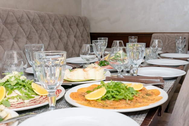 Foto mesa festiva, jantar em família servido com antepastos italianos - salmão marinado, hamon, carpaccio, pera, manjericão tablescape.