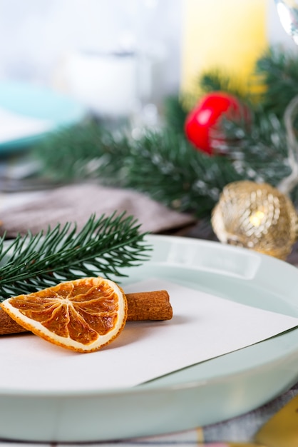 Mesa festiva de Navidad y Año Nuevo con naranja seca y canela sobre un tejido gris. Comedor decorado