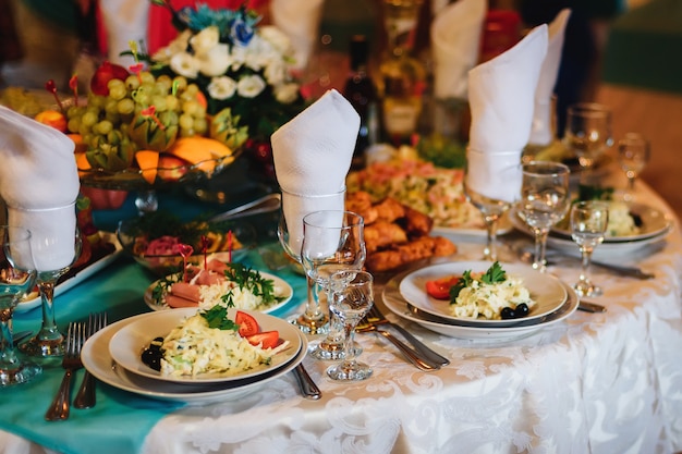 Mesa festiva no restaurante com pratos, copos e talheres em uma toalha de mesa branca