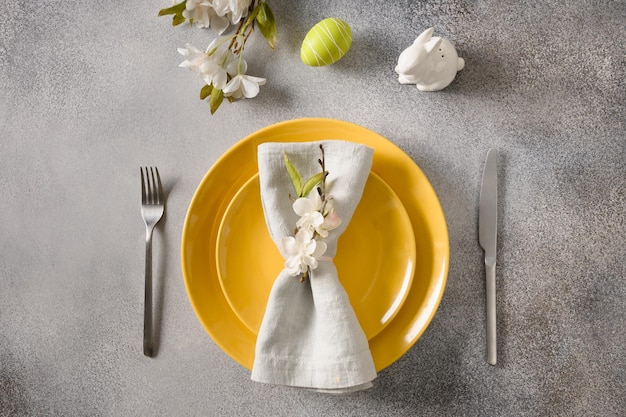 Mesa festiva de Pascua con flores de primavera de plato amarillo y huevos de colores verdes