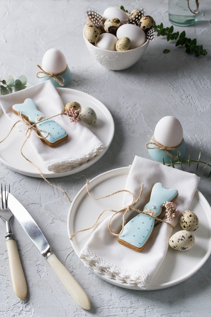 Mesa festiva de Pascua con galletas de conejito de Pascua, huevos de codorniz y huevo de gallina, ramitas de hojas verdes de eucalipto. . Decoraciones de celebración navideña.