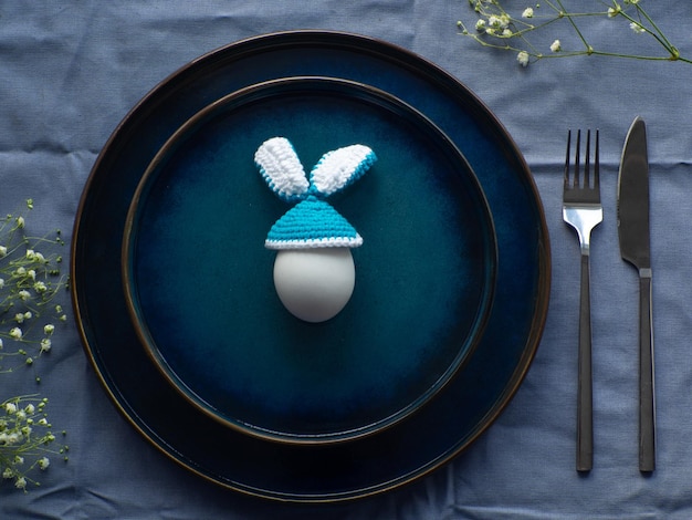 Mesa festiva de Pascua con huevo y flores sobre fondo azul.