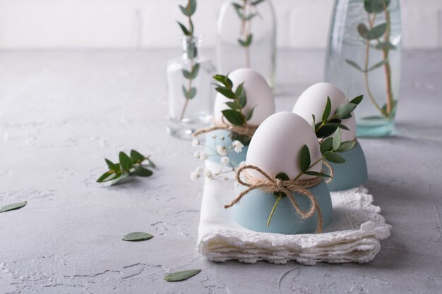 Mesa festiva de Pascua con huevos de gallina blanca en hueveras, ramitas de eucalipto. .