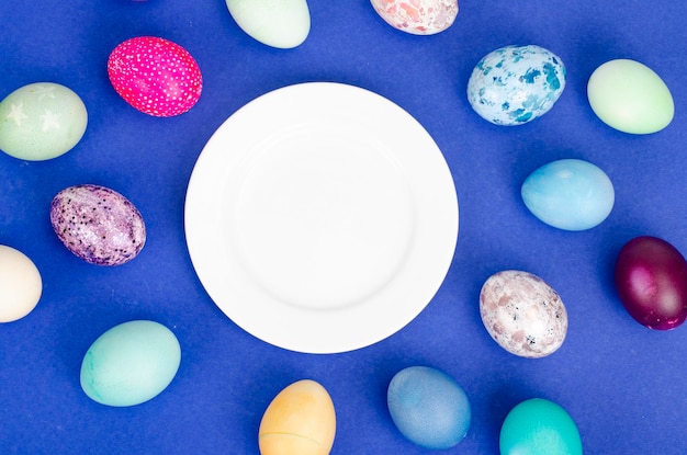 Mesa festiva de Pascua con huevos pintados sobre fondo azul. Espacio para texto. Foto de estudio