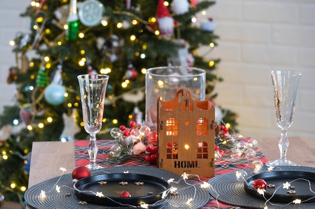 Mesa festiva posta na sala de estar para o Natal e Ano Novo em estilo loft árvore de Natal preto pratos e garfos guardanapos tecidos utensílios de mesa da moda interior aconchegante da casa