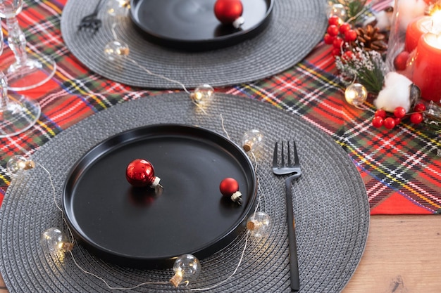 Mesa festiva en la sala de estar para Navidad y Año Nuevo en estilo loft Árbol de Navidad platos negros y tenedores servilletas tejidas vajilla de moda interior acogedor de la casa