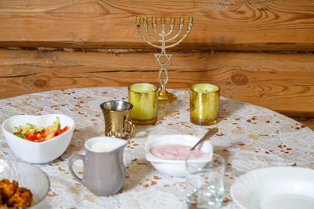 Una mesa festiva de Shabat con velas encendidas y una menorá
