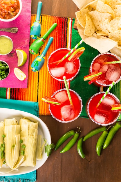 Foto mesa de fiesta con tamales, margaritas de fresa y pan dulche.
