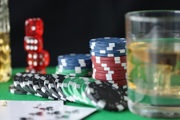 En la mesa hay fichas para cartas de casino y un vaso de alcohol. Concepto de adicción al juego