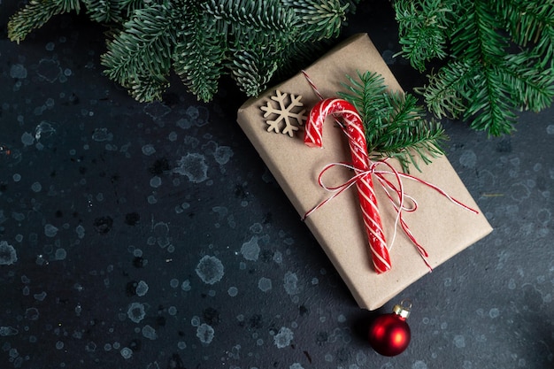 En la mesa hay un regalo rodeado de ramas de árboles de Navidad, juguetes de madera y especias.