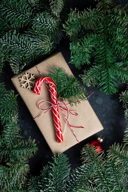 En la mesa hay un regalo rodeado de ramas de árboles de Navidad, juguetes de madera y especias.