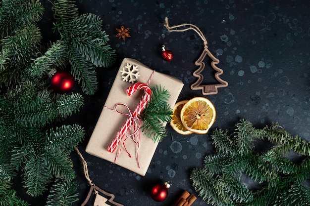 En la mesa hay un regalo rodeado de ramas de árboles de Navidad, juguetes de madera y especias.