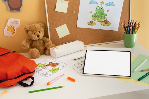 Foto mesa infantil em ângulo elevado com bolsa de livro e tablet