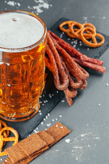 Mesa con jarra de cerveza y tabla de madera con salchichas