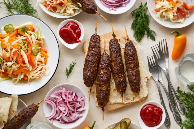 Mesa con kebab de ternera, ensalada fresca y hierbas.