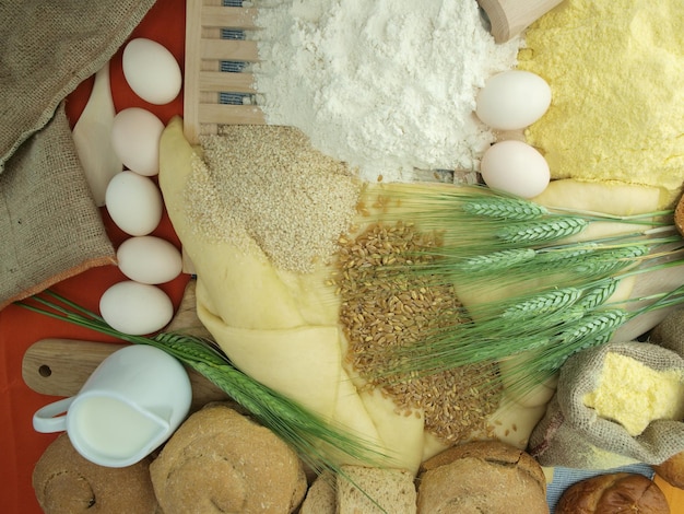 Una mesa llena de pan, harina y otros ingredientes, incluida la harina.