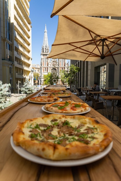 Foto una mesa llena de pizzas con una iglesia al fondo