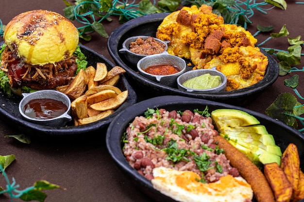 Foto una mesa llena de platos de comida vegana que incluyen una hamburguesa, papas y una guarnición de salsa.