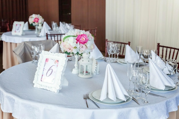 Mesa de lujo puesta para la cena con composición de flores en el restaurante boda de fondo interior de lujo