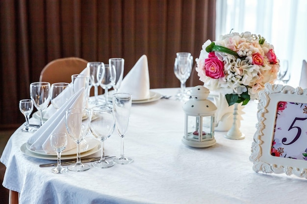 Mesa de lujo puesta para la cena con composición de flores en el restaurante boda de fondo interior de lujo