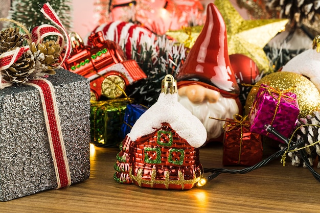 Mesa de madera con adornos navideños. Bolas rojas, plateadas y doradas, cajas de regalo, luces, Papá Noel, Panettone, árbol de Navidad y otros. Enfoque selectivo.