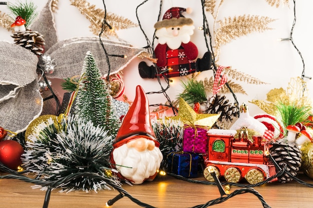 Foto mesa de madera con adornos navideños. bolas rojas, plateadas y doradas, cajas de regalo, luces, papá noel, panettone, árbol de navidad y otros. enfoque selectivo.