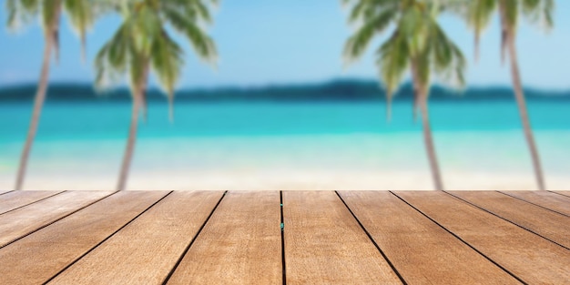 Mesa de madera antigua vacía frente a un fondo borroso de palmeras de arena y fondo de playa tropical en vacaciones de verano y concepto de viaje con espacio para copiar