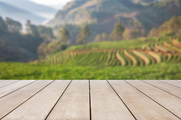 Mesa de madera antigua vacía frente a la hermosa vista borrosa de la plantación de té y la montaña con un hermoso fondo de amanecer de la naturaleza Se puede usar para exhibir o montar para mostrar sus productos