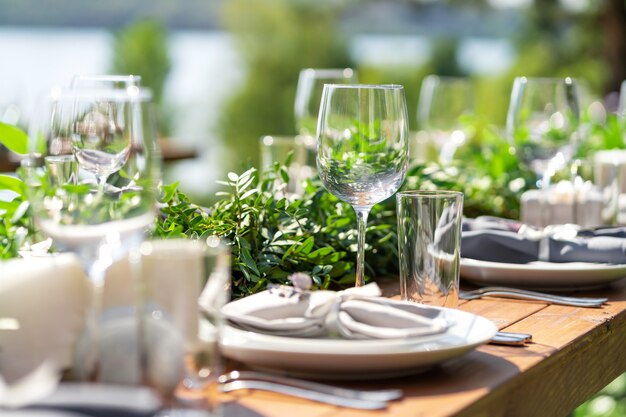 Mesa de madera bellamente decorada en un café de verano al aire libre. Decoración de mesa de rama verde y flores frescas