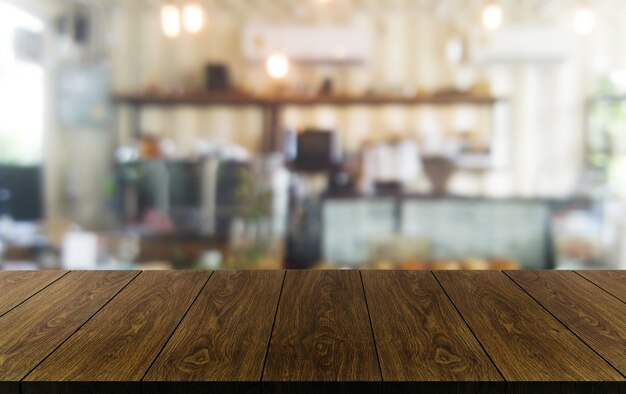 Mesa de madera borrosa de la moderna sala de restaurante o cafetería para maqueta de exhibición de productos.