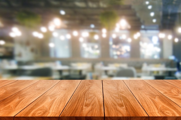 Mesa de madera borrosa de la moderna sala de restaurante o cafetería para maqueta de exhibición de productos.