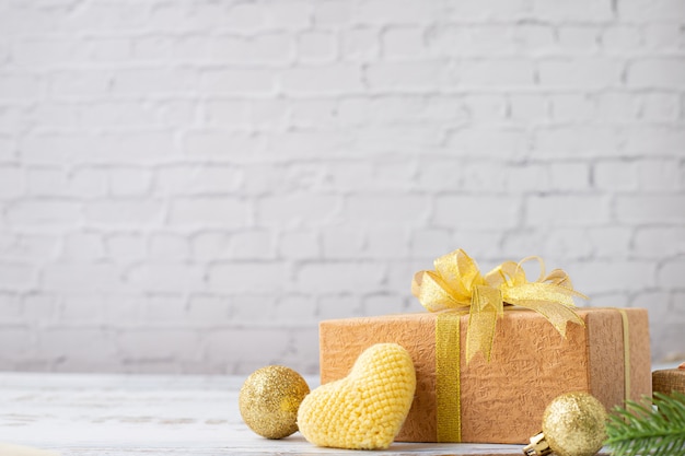 Foto mesa de madera con caja de regalo y símbolo en forma de corazón amarillo sobre textura de pared de ladrillo blanco