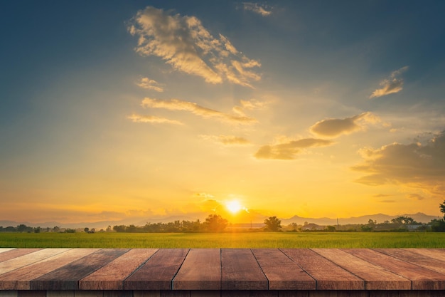 Mesa de madera y campo de arroz y cielo azul al atardecer con montaje de pantalla de destello de lente para el producto